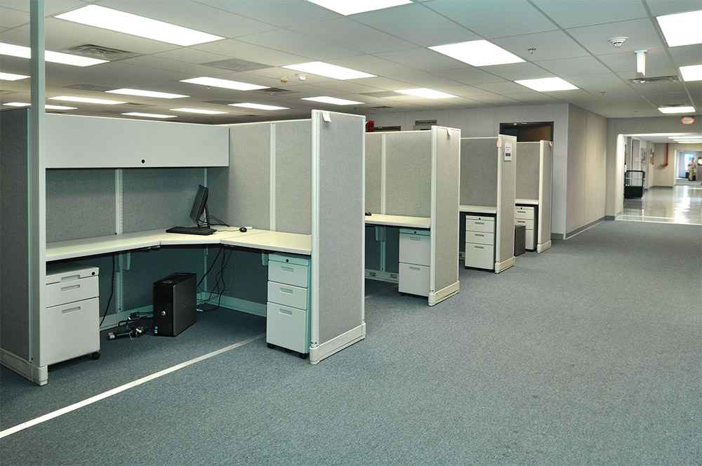 Interior view of a modular office space with multiple gray cubicles, desks, and computer in USA